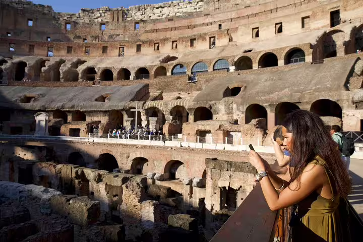Woman taking photos from the Colosseum arena floor overlooks underground chambers on an exclusive gladiators tour in Rome