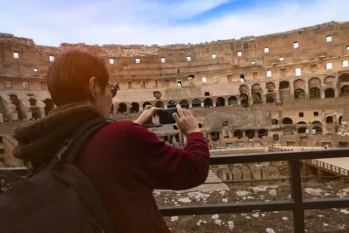 Visitor taking photos from the Colosseum gladiators arena floor on an exclusive guided tour in Rome, Italy