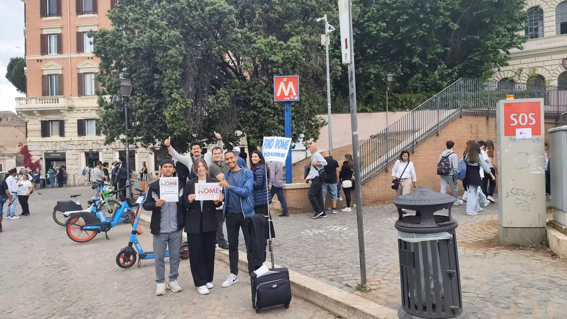 Visitors gather at a meeting point near the Colosseum for a guided Rome tour, surrounded by historic architecture.