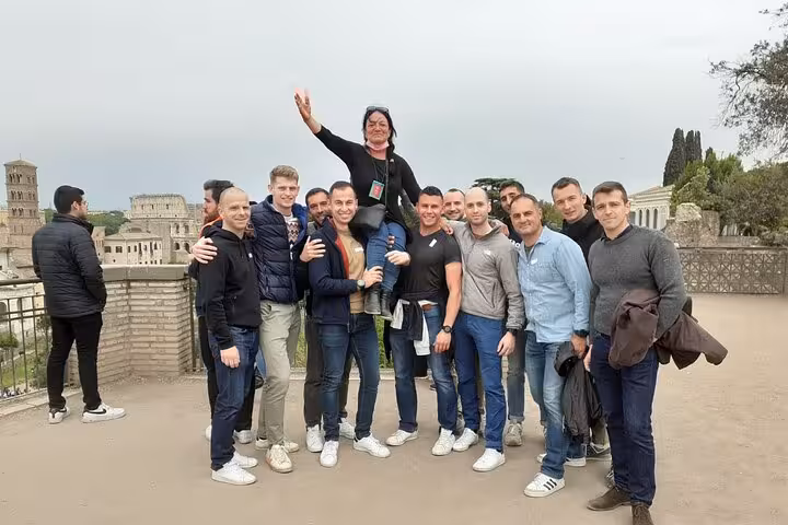 Tour group celebrating at the Colosseum's terrace with panoramic views, showcasing unforgettable Roman sightseeing.