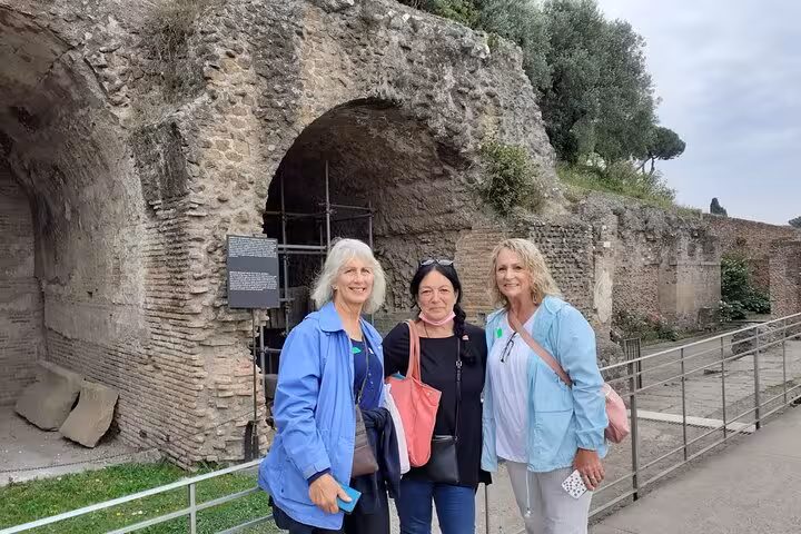 Three tourists smiling at the Colosseum entrance, capturing the excitement of a guided tour in Rome's historic site.