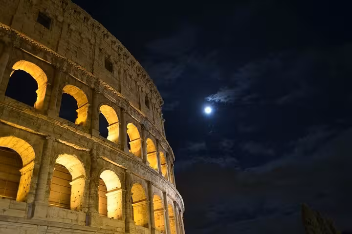 Experience the Colosseum illuminated under a moonlit sky, showcasing its grandeur on a private night tour of Rome's iconic landmark.