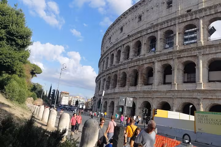 Tourists explore the exterior of Rome's iconic Colosseum, offering a glimpse into ancient history on a private tour.