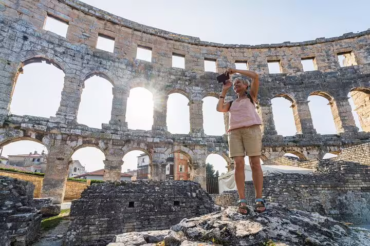 Senior traveler photographing ancient Roman arena walls during private Colosseum tour with expert guide in Rome, Italy
