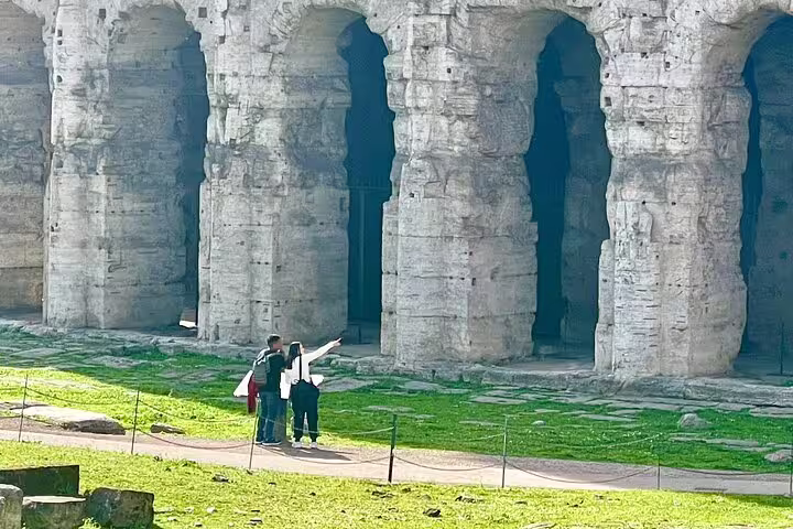 Small group with guide exploring massive stone arches of the Colosseum on a private Best of Rome walking guided tour