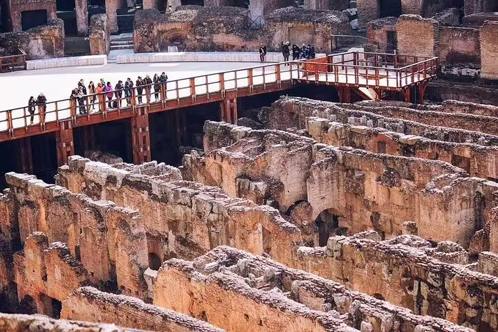 Tour group walking on elevated platform above Colosseum hypogeum ruins during official guided visit with Palatine Hill access