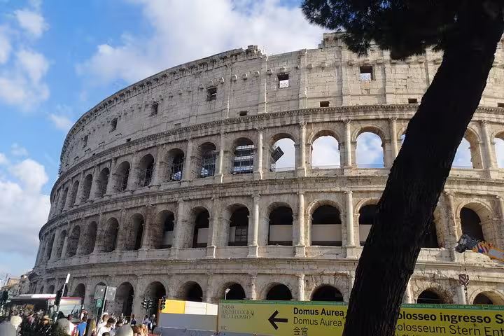 The majestic exterior of the Colosseum in Rome stands under a bright blue sky, attracting tourists on a private tour.