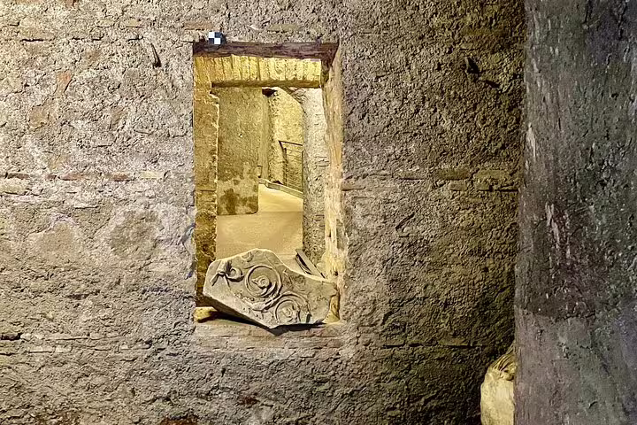 Underground stone corridor and carved marble fragment inside the Colosseum on a Rome Forum and Palatine Hill tour