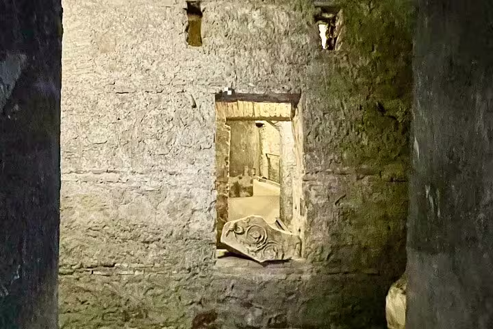 Stone passageway and carved relics in the hidden tunnels of the Colosseum, visited on a Rome Forum and Palatine Hill history tour