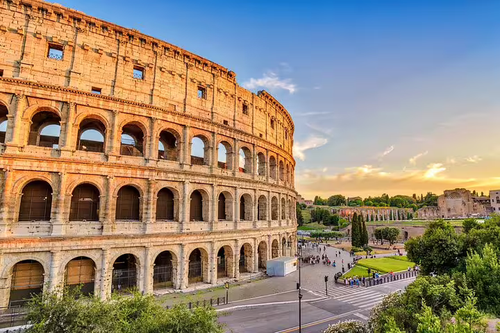 Close-up exterior of the Colosseum at sunset with visitors gathering for a private arena floor tour led by a local guide
