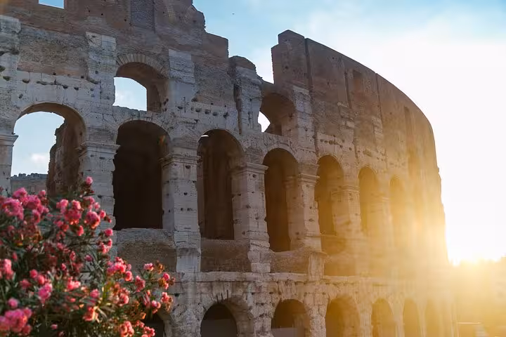 Colosseum at sunset with flowers, iconic stop on Rome walking tour before hosted access to the Vatican