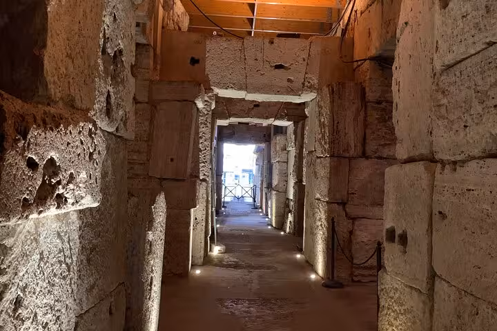 Illuminated ancient stone corridor in the Colosseum underground, part of the exclusive guided tour experience.
