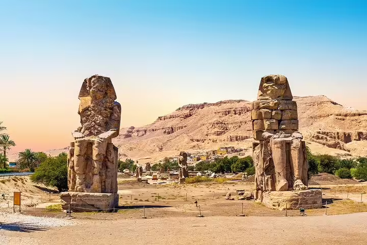 Colossi of Memnon statues on a private Luxor day tour from Cairo by plane with desert hills backdrop