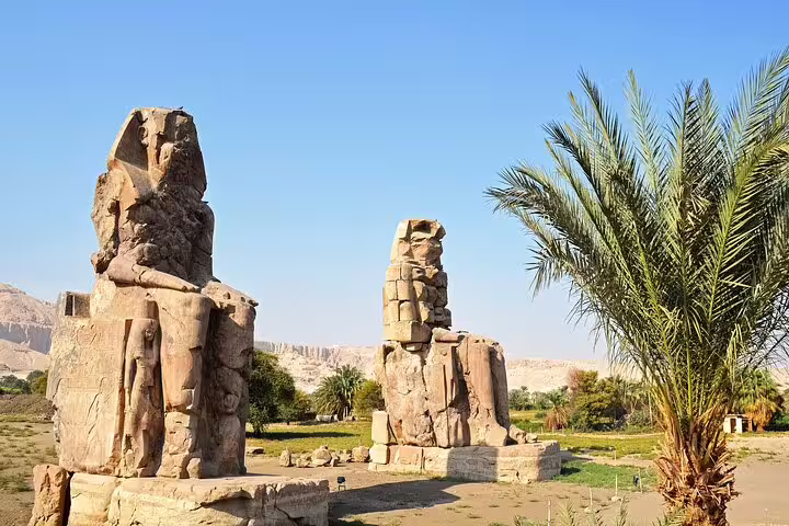 Colossi of Memnon statues in Luxor with palm trees, must-see on 5 days 4 nights Splendours of the Nile tour