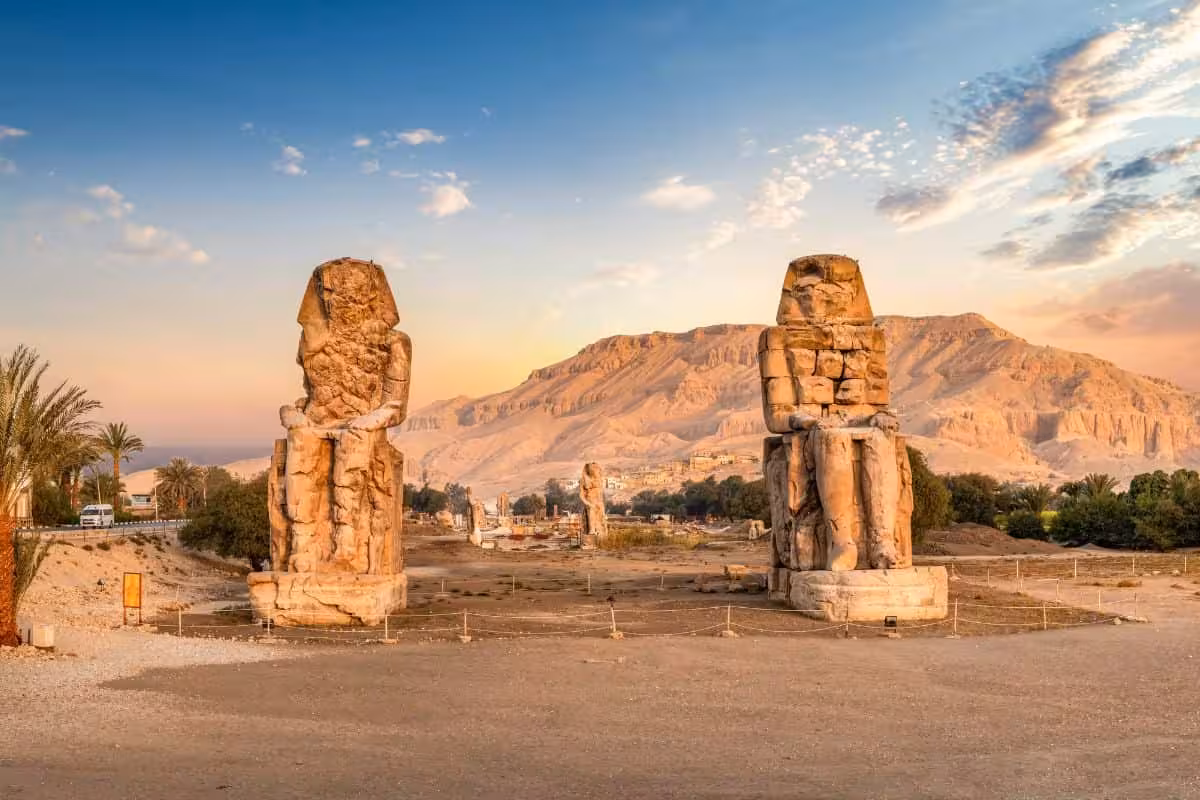Colossi of Memnon statues at sunset, West Bank stop on Luxor full-day tour with Thebes mountains backdrop