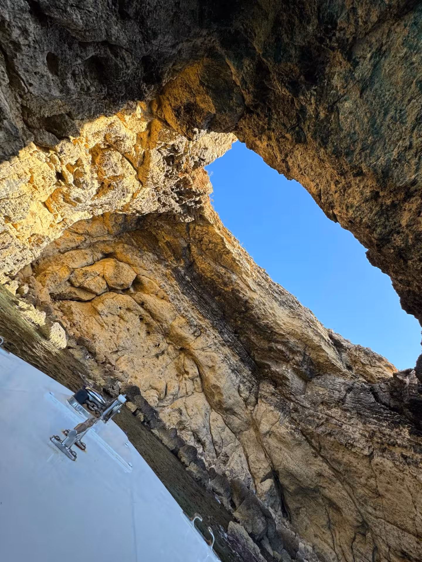 Boat entering Comino sea cave on Blue Lagoon and Crystal Lagoon sunset tour, limestone cliffs and clear water, Malta