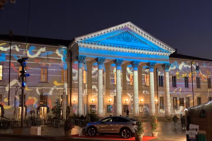 Como city center neoclassical building lit at night, featured on Milan to Lake Como, Bellagio and cruise trip