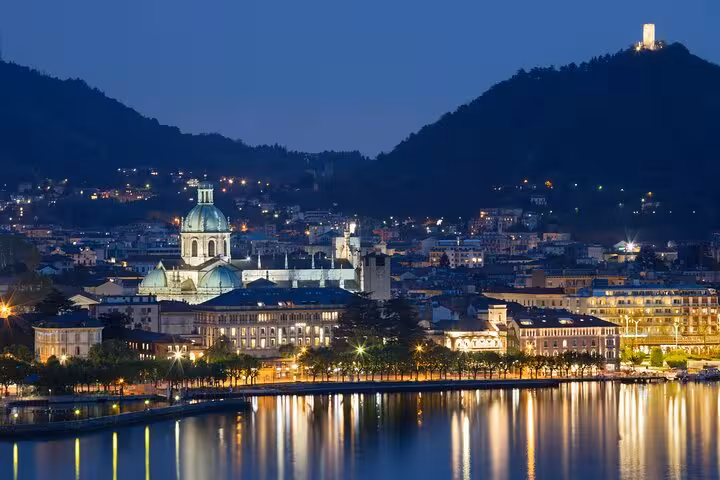 Night view of Como waterfront and Duomo lights reflecting on Lake Como, highlight of guided boat tour