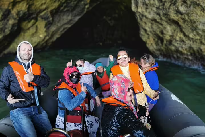 Tourists enjoy a boat trip exploring the stunning Benagil caves during a Comporta to Algarve private tour adventure.