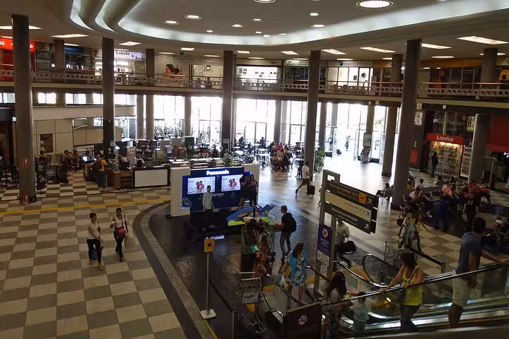 Interior of Congonhas Airport bustling with travelers, shops, and escalators, ideal for private transfer to São Paulo hotels.