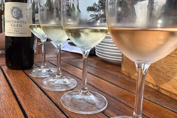 Close-up of chilled white wine glasses on a wooden table at Constantia Glen, showcasing a premium wine-tasting experience.