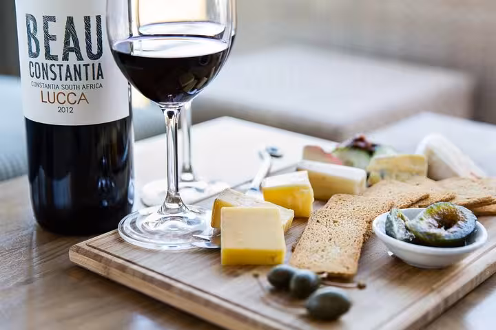 Beau Constantia wine paired with cheese and crackers on a wooden board, perfect for a gourmet wine tasting experience.