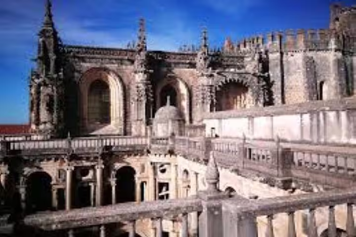 Exterior view of the Convent of Christ in Tomar, showcasing its stunning Gothic architecture under a clear blue sky.