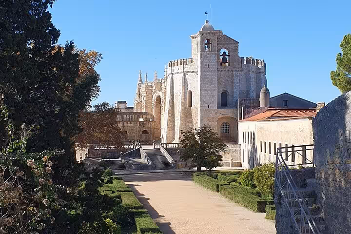 Explore the stunning Convent of Christ in Tomar, showcasing its medieval architecture amidst lush gardens and history.