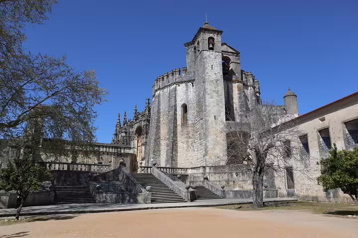 Exterior view of the Convent of Christ in Tomar, highlighting its medieval architecture and grand staircase.