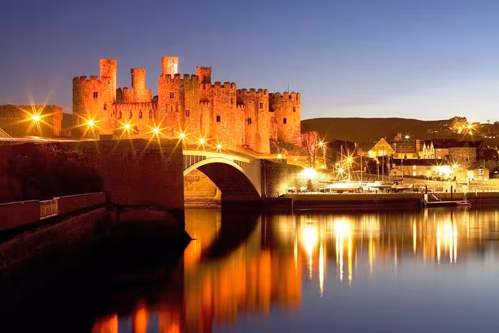 Conwy Castle at dusk with bridge and waterfront reflections, highlight of the Snowdonia & 3 Castles Tour