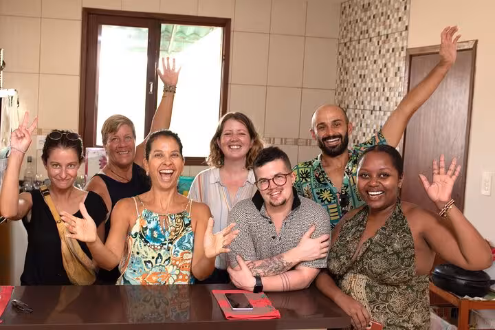 Joyful group of cooking class participants celebrating their Bahian culinary experience in a lively Salvador kitchen.