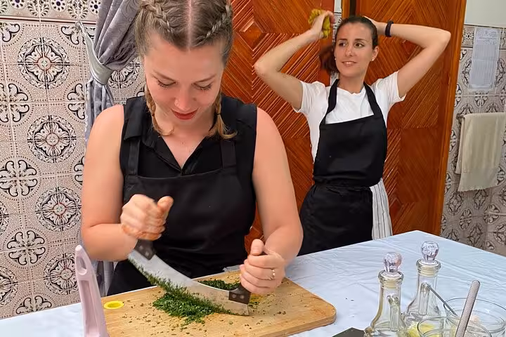 Participants in a cooking class with Yassine & Mom chopping herbs in a Moroccan-style kitchen.