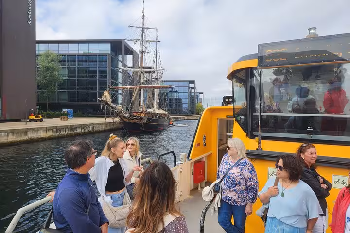 Tourists on a ferry near a historic ship in Copenhagen canal on the Walk & Ferry tour.