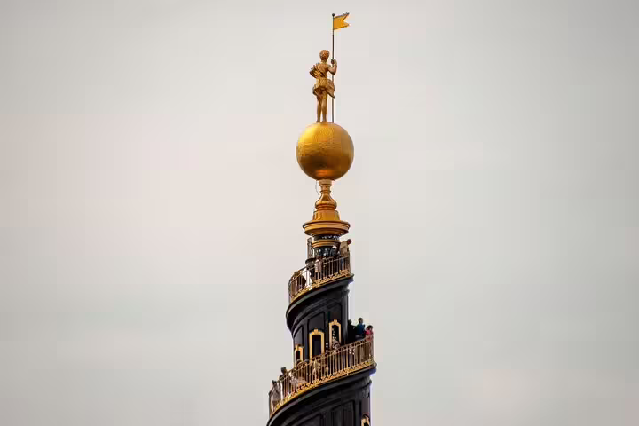 View of the iconic spiral tower of Church of Our Saviour in Copenhagen, featuring golden globe and statue, perfect for a private tour.