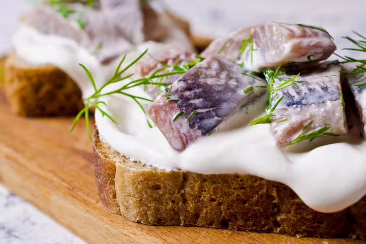 Open-faced Danish sandwich with marinated herring and dill on rye bread, featured in Copenhagen Private Full Day Tour.
