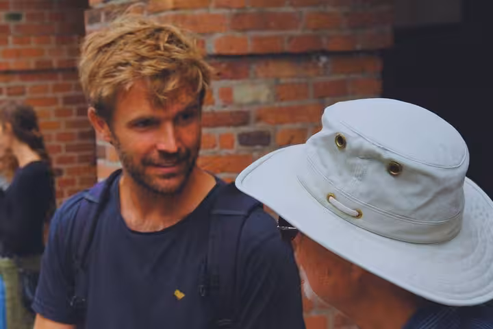 Tour guide engaging in a lively conversation with a visitor against a brick wall backdrop in Copenhagen.