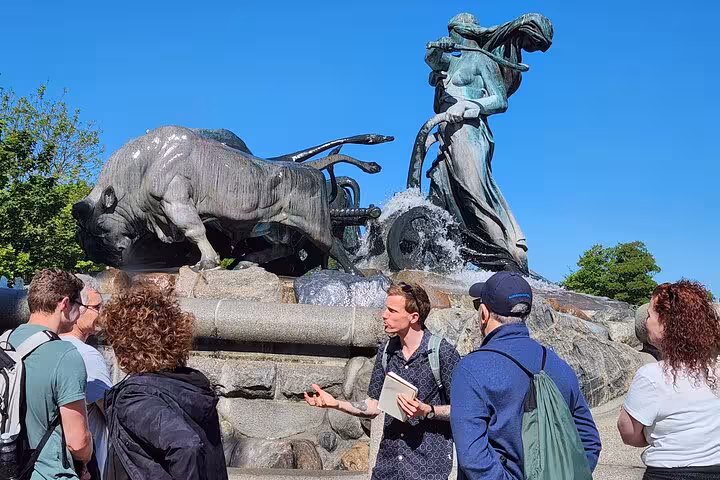 A tour guide explains the history of the Gefion Fountain to a group of tourists in Copenhagen.