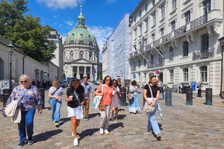 Tourists exploring Copenhagen with the Marble Church in the background on a sunny day.
