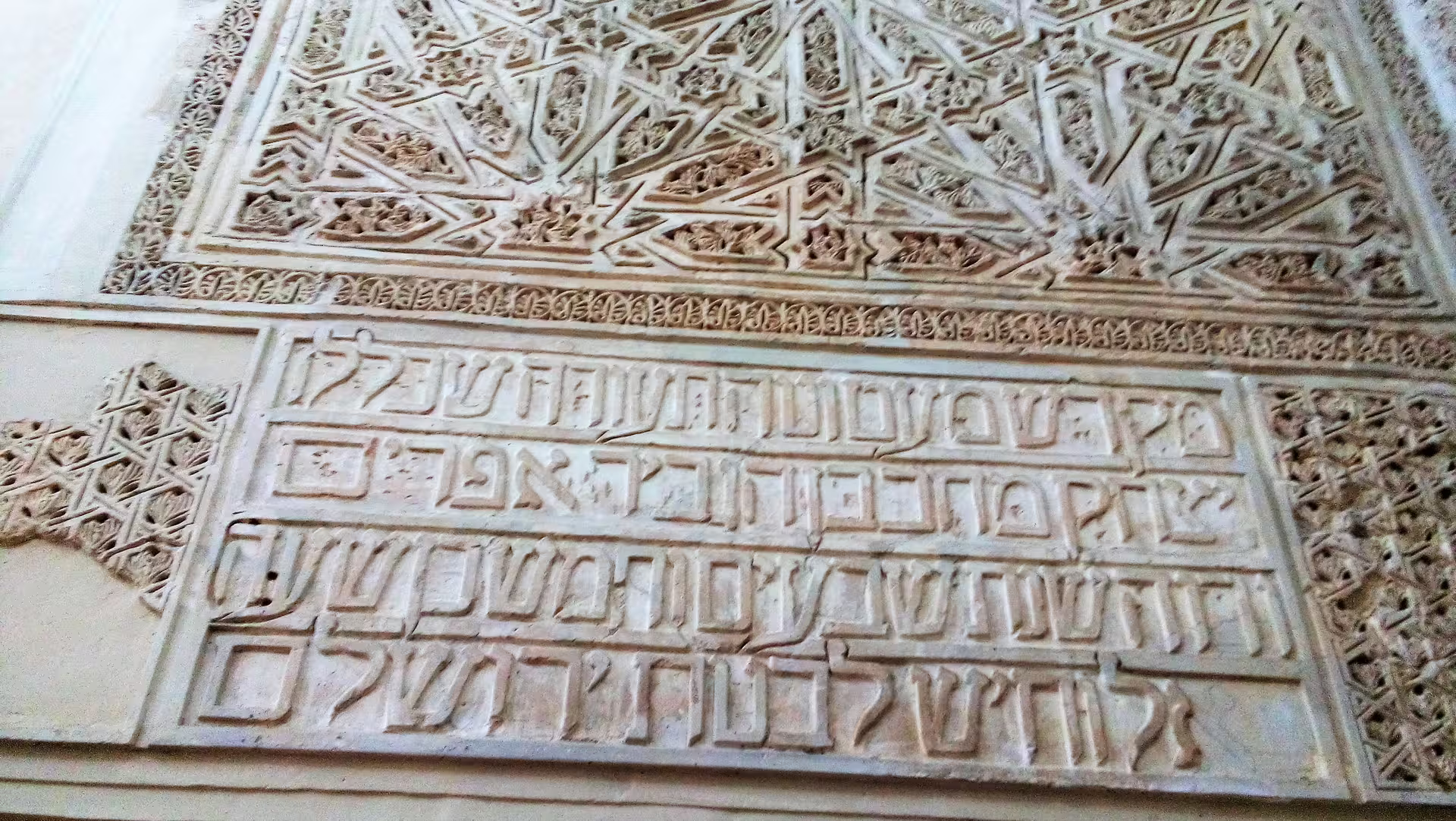 Close-up of intricate Arabic calligraphy and geometric plasterwork on a Cordoba group walking tour at the Alcazar
