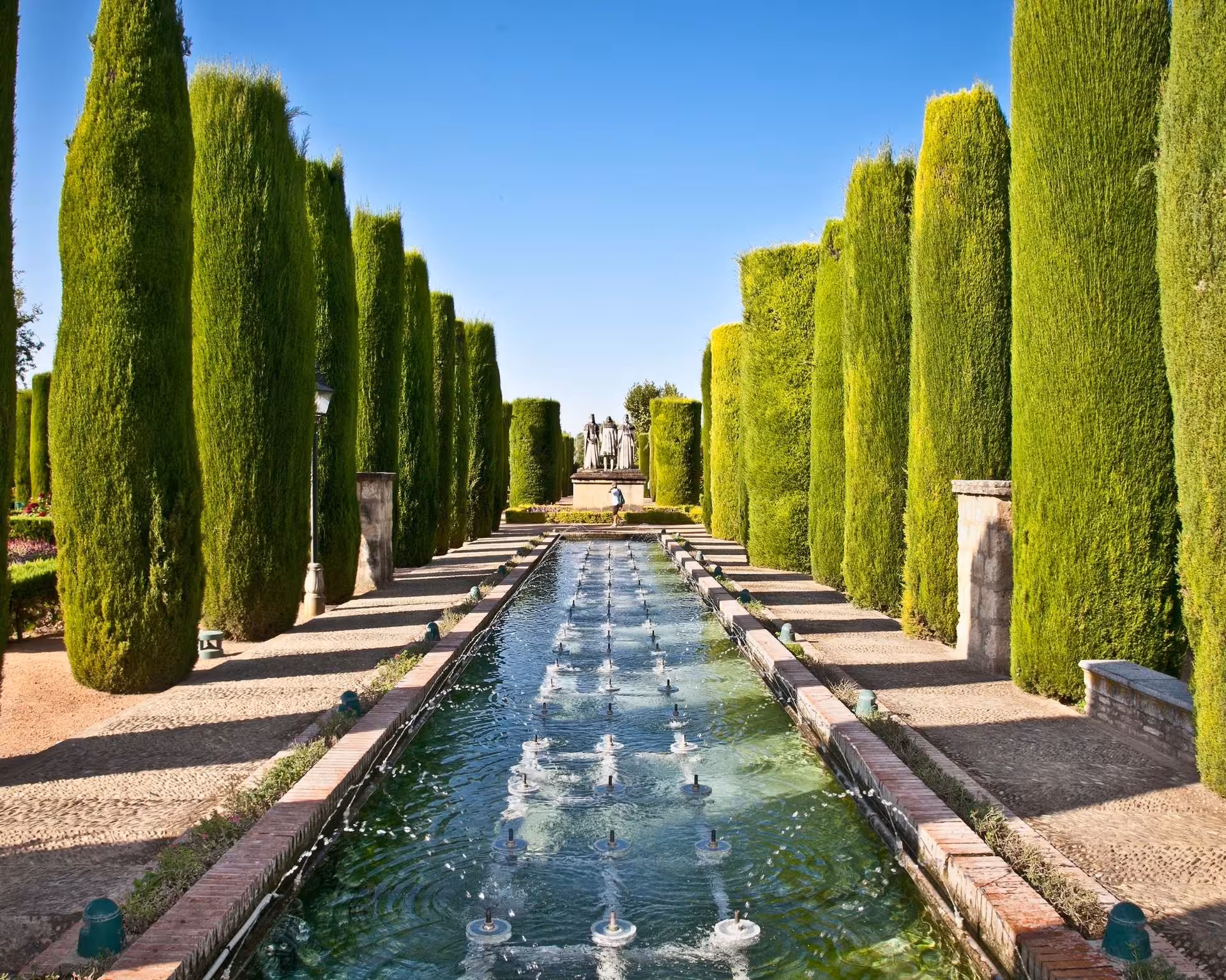 Jardines del Alcázar de Córdoba con canal y cipreses, parada del tour Encantos Locales antes del tablao flamenco
