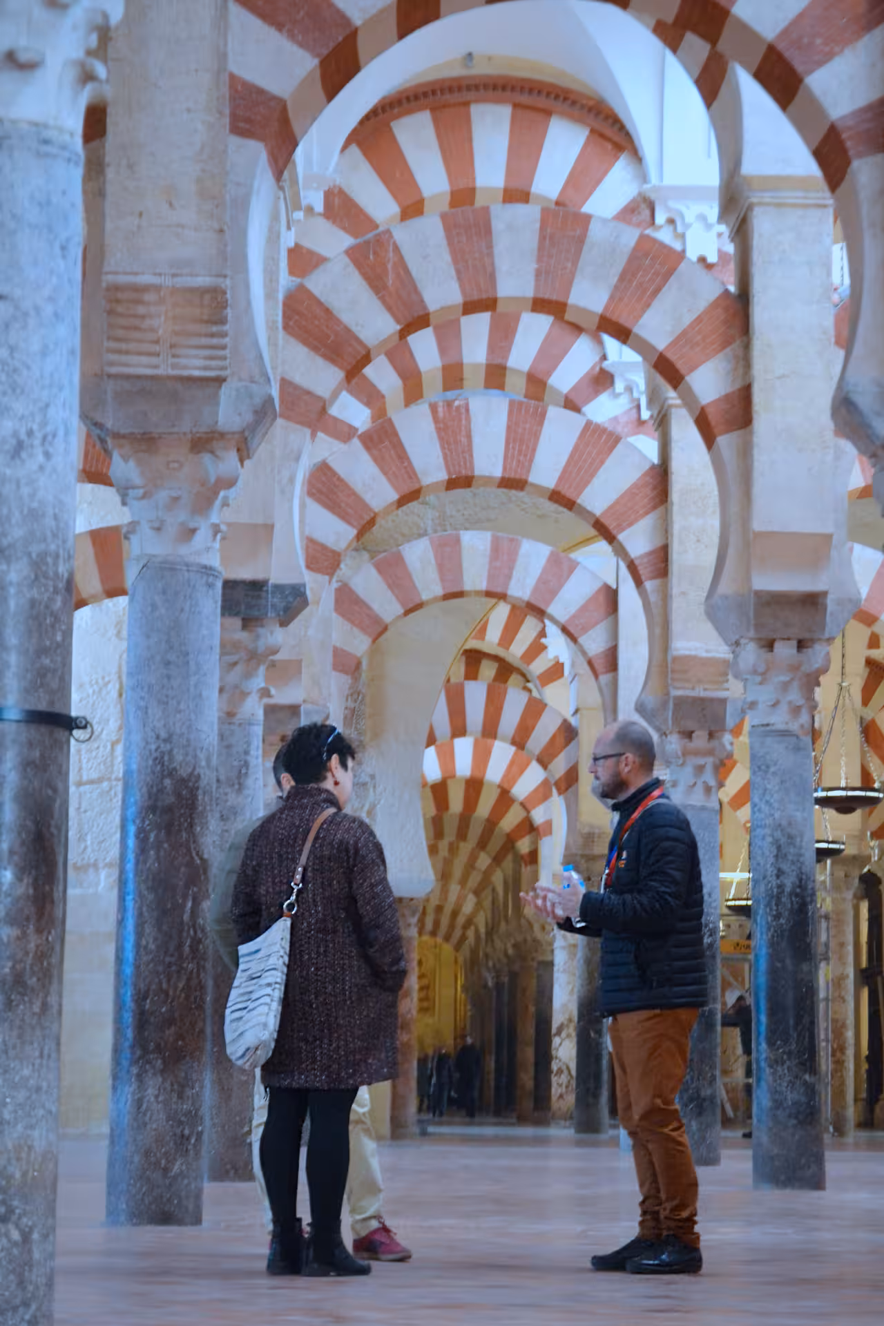 Visitors explore the iconic arches inside the Cathedral Mosque in Cordoba during a guided cultural tour.