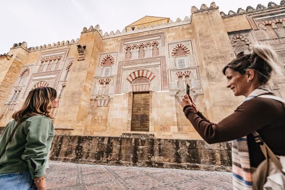 Tourists capturing the intricate façade of the Mezquita-Catedral in Córdoba during a guided tour.
