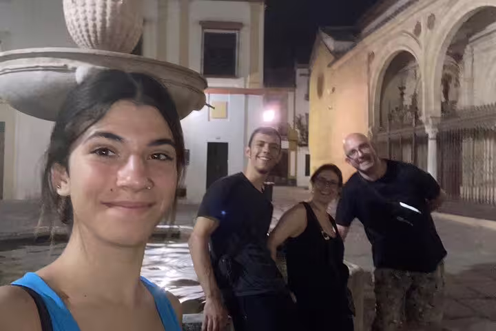 Group selfie at night in Córdoba old town near a fountain, joining a scavenger hunt city highlights walk