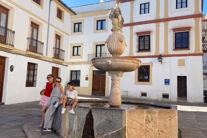 Travelers relax by a historic Córdoba plaza fountain on a scavenger hunt and city highlights walking tour