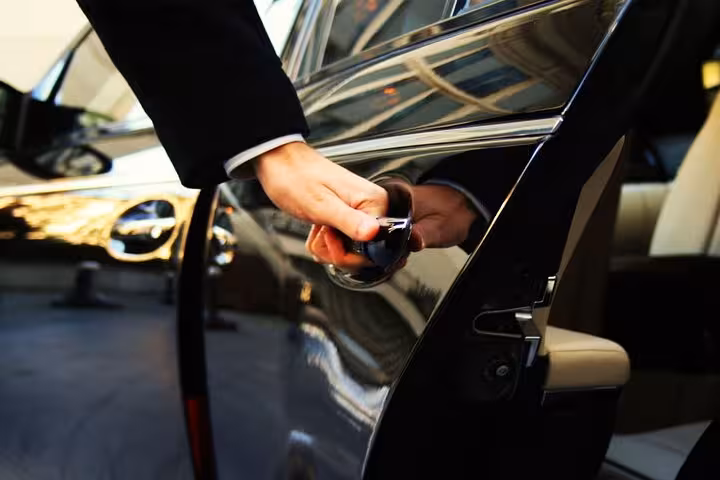 Driver opening black car door for passenger, Corfu private transfer from airport or port with meet and greet