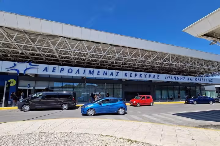 Corfu International Airport terminal exterior with vehicles, meet-and-greet for private transfer to port or hotel