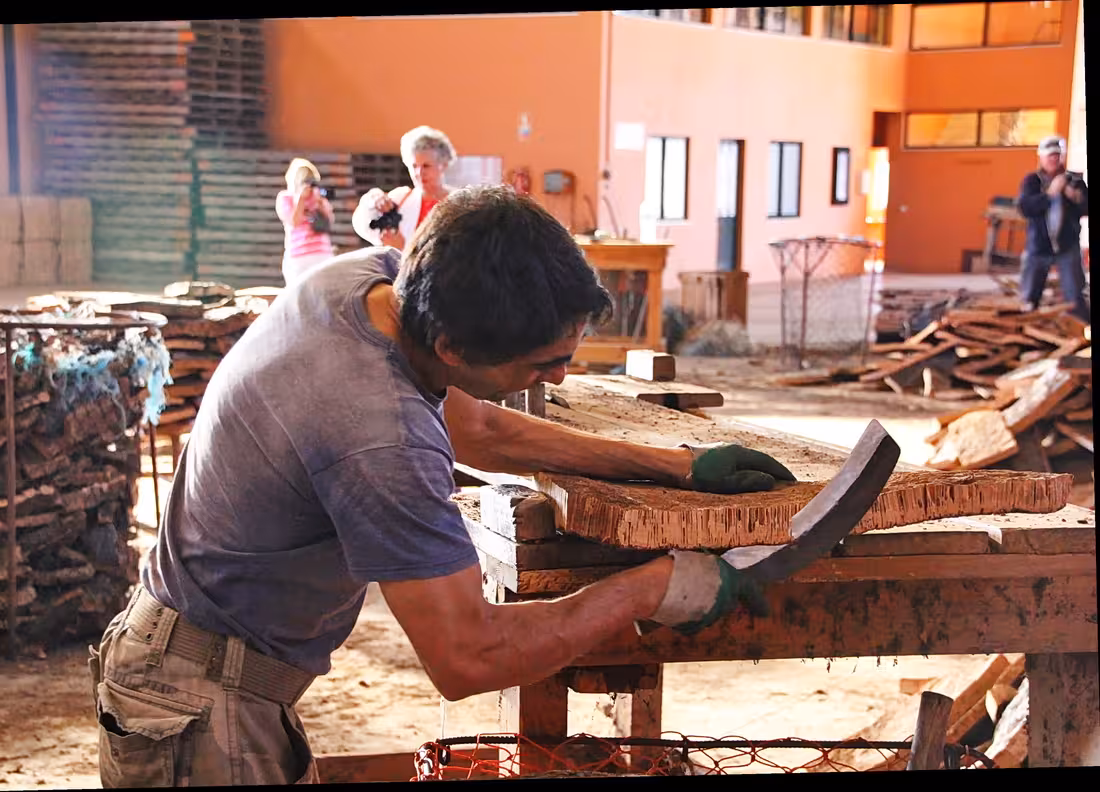 Worker trimming cork bark during São Brás de Alportel cork factory visit with expert guide in Algarve