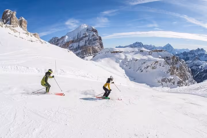 Two skiers gliding down snowy slopes in Cortina d'Ampezzo, highlighting winter sports before Venice transfer.