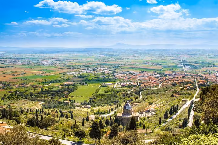 Breathtaking panoramic view of Cortona's rolling landscape from Florence, showcasing lush greenery and historic architecture.