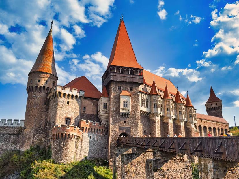 Magnificent Corvin Castle with soaring Gothic towers and wooden bridge on a sunny Transylvania guided tour